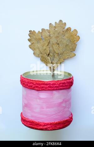 Un rametto con foglie di quercia secca in un vaso rosa di teglia. Foto Stock