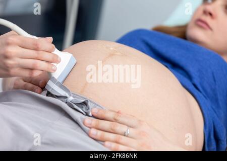 Vista ravvicinata del trasduttore a ultrasuoni sull'addome di una donna incinta. Ufficio di Ginecologia. Foto Stock