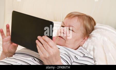 donna anziana con un dispositivo mobile in mano. Foto Stock