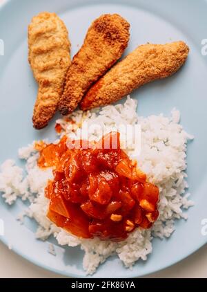 Piatto con menu per bambini di strisce di pollo impanate e riso con salsa di pomodoro Foto Stock