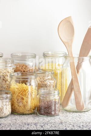 Varietà di cereali, cereali, pasta, semi in vasetti di vetro non cotti su fondo bianco della cucina, closeup, rifiuti zero, eco-friendly, alimentazione a dieta equilibrata, lui Foto Stock