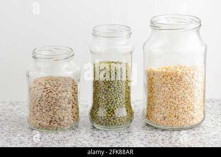 Varietà di legumi secchi: Lenticchie, piselli, grammo verde in vasi di vetro non cotti su sfondo bianco della cucina, zero rifiuti, eco-friendly, dieta equilibrata alimentare, lui Foto Stock