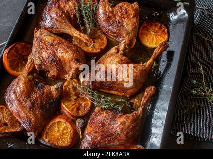 Cosce d'anatra cotte al forno italiano con arance, miele, salsa di timo servite su una teglia da forno dall'alto Foto Stock