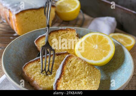 Un piatto con fette di torta al limone su un tavolo rustico sfondo con tong torta Foto Stock