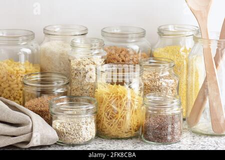 Varietà di cereali, cereali, pasta, semi in vasetti di vetro non cotti su fondo bianco della cucina, closeup, rifiuti zero, eco-friendly, alimentazione a dieta equilibrata, lui Foto Stock