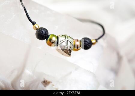 Elegante bracciale con perline minerali su corda nera su brillante naturale sfondo Foto Stock