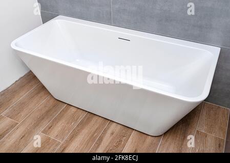Una moderna vasca indipendente a parete, senza rubinetto, in un bagno rivestito di piastrelle in ceramica. Foto Stock
