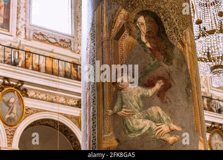 Primo piano sull'affresco religioso medievale che mostra la Vergine Maria che tiene il bambino Gesù dipinto sulla colonna della cattedrale cattolica di Roma Foto Stock