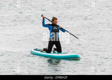 West Bay, Dorset, Regno Unito. 29 aprile 2021. Regno Unito Meteo. Un paddle boarder godendo il mare calmo presso la località balneare di West Bay in Dorset, il giorno di nuvole e caldi incantesimi di sole. Picture Credit: Graham Hunt/Alamy Live News Foto Stock