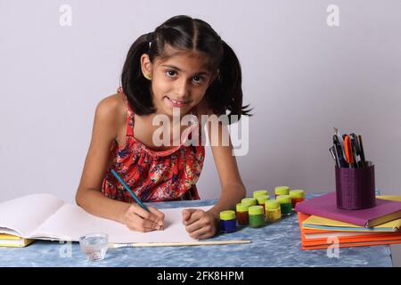 Ragazza asiatica indiana godendo di pittura a casa con carta, colore dell'acqua e pennello d'arte. Foto Stock