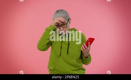 La donna anziana usa il telefono cellulare perde diventando sorpresi improvvisi risultati della lotteria, la sfortuna, la perdita Foto Stock