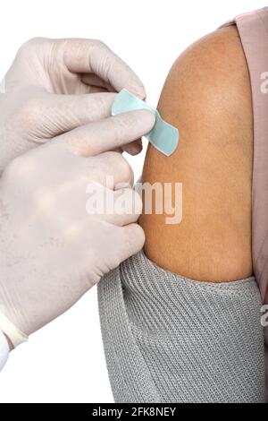 Vista ritagliata del medico in guanti di lattice applicando il cerotto adesivo sul braccio di donna anziana isolato su bianco Foto Stock
