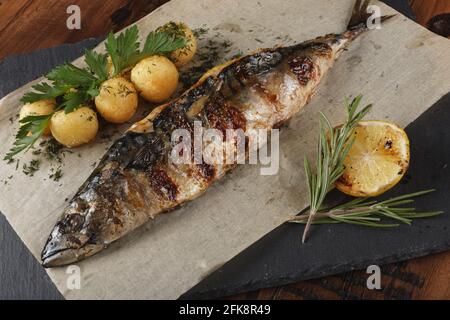 Sgombro fritto ripieno di limone. Palle di patate giovani su superficie di ardesia. Sfondo di legno Foto Stock