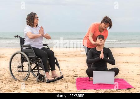 Gruppo di donne che praticano la meditazione in spiaggia: Fuoco selettivo: Concetto di salute e meditazione. Foto Stock