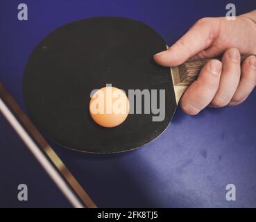 l'uomo sta giocando a ping pong. Tiene la racchetta nelle mani Foto Stock