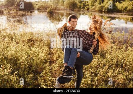 Una coppia innamorata nel campo. Donna che cavalcano un ragazzo, gioco divertente. Foto Stock