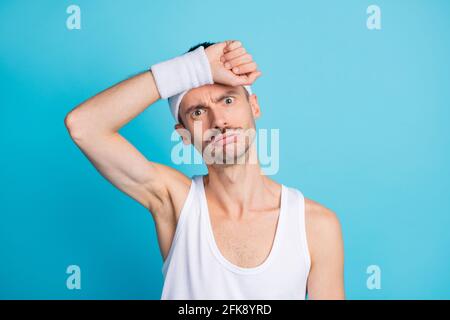 Foto di stanco giovane uomo tenere mano testa esercizio esausto allenamento in palestra isolato su sfondo blu Foto Stock