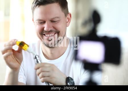 L'uomo sorridente riempie il vaporizzatore di marijuana per fumare e scatta foto Foto Stock