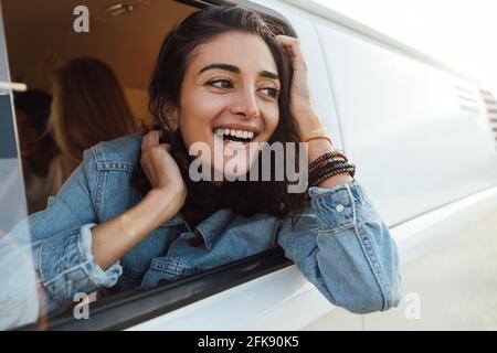 Donna felice che ama il giro in auto. Bella giovane donna che guarda fuori dal furgone. Foto Stock