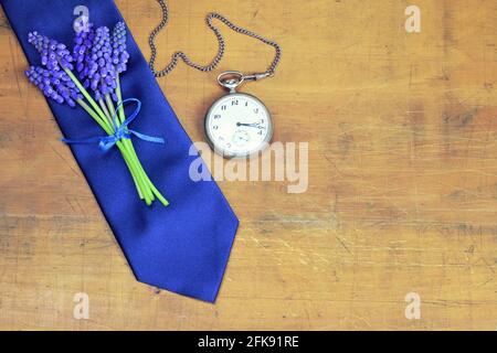 Regalo del giorno dei padri. Cravatta blu, fiori muscari e orologio da tasca vintage su sfondo di legno con spazio per la copia Foto Stock