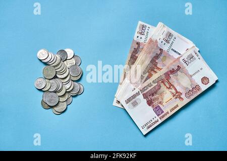 Molte piccole monete russe e banconote da cinque mila dollari su sfondo blu, il concetto di denaro Foto Stock