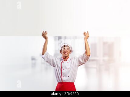 Giovane chef maschile con un cartello bianco vuoto Foto Stock