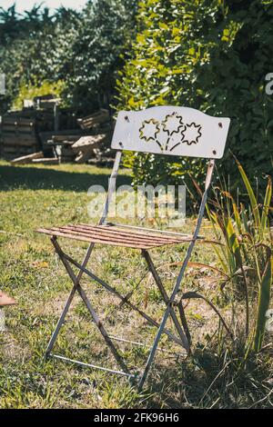 Sedia pieghevole in metallo d'epoca con ornamento in giardino Foto Stock