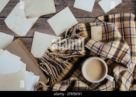 Cornici chiare vuote per posizionare le foto o il testo su sfondo di legno con tazza di caffè e bruno accogliente plaid. Composizione calda in stile retrò Foto Stock