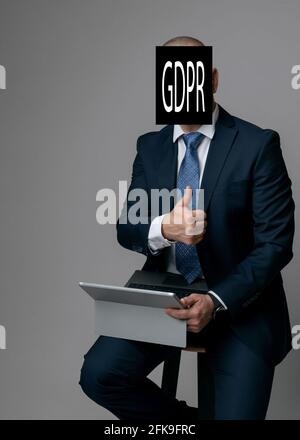 L'uomo d'affari elabora una nota con il titolo della legge sulla protezione dei dati GDPR e tiene un pollice in su. copyspace. Foto Stock