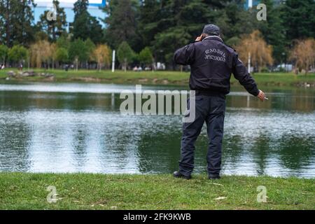 poliziotto che parla al telefono sullo sfondo del lago Foto Stock