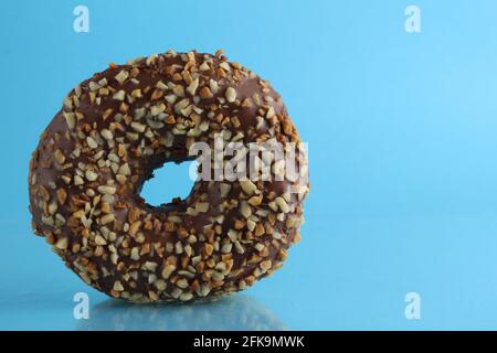 Il cioccolato Berliner Donut rosa si trova su uno sfondo blu e luminoso con un luogo in cui scrivere una copia del pasto per la colazione still life. Foto Stock