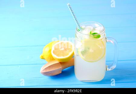 Limonata ghiacciata di lavanda, limone, paglia, menta. Cocktail classico di mojito vergine, bevanda analcolica con ghiaccio, vasetto vintage in vetro di muratura di legno blu Foto Stock
