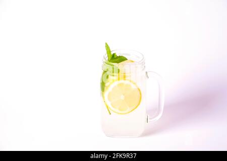 Limonata ghiacciata di lavanda, limone, paglia. Cocktail classico di mojito vergine, bevanda analcolica con ghiaccio in vasetto di vasetto vintage su isolo bianco brillante Foto Stock