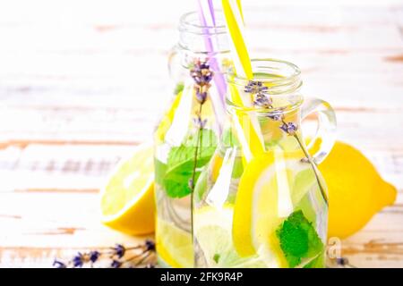 Limonata ghiacciata di lavanda, limone, paglia. Due classiche bevande vergini mojito, cocktail analcolico con ghiaccio in due bottiglie d'hipster d'epoca, gruntate Foto Stock