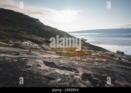 Immagine panoramica del Camp a Eqi Sermia Eqip ghiacciaio in Groenlandia. natura paesaggio con lodge cabine. Il sole di mezzanotte e rosa del cielo. Destinazione turistica Foto Stock