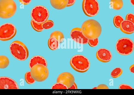 Idea minima con pompelmo fresco affettato su sfondo blu alla moda. Concetto minimo di frutta.vitamine, concetto sano di dieta. Pompelmo intero e affettato Foto Stock