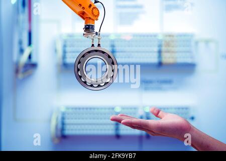 Primo piano Robotica industriale presa di metallo per l'invio alla mano umana su colore smart factory blu tono sfondo sfocato, industria 4.0 Foto Stock
