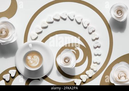 Tazza da caffè, cerchi Fibonacci in carta marrone e cuori di zucchero. Latte art con design floreale, gustosa perfezione. Concetto di rapporto d'oro Foto Stock