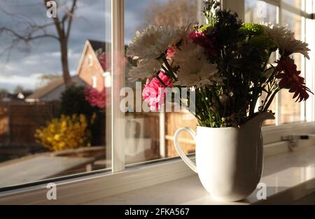 Primo piano di un bouquet di fiori colorati in ceramica caraffa su un davanzale Foto Stock