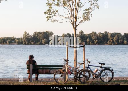 Foto di una coppia anziana, uomo anziano e donna, che dorme e si fa una pausa su una panchina dopo aver fatto un giro in bicicletta lungo il fiume danubio a Belgrado, serbia. Foto Stock