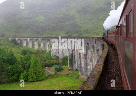 Treno a vapore che passa sul viadotto Glenfinnan nella Scozia rurale Foto Stock