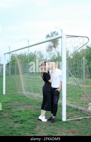 Giovane donna che baciano l'uomo nell'obiettivo di calcio. Foto Stock