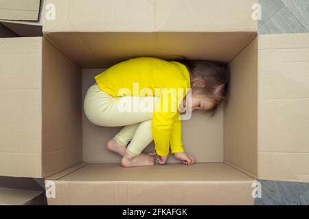 una ragazza triste si trova in una scatola per il trasferimento a. un nuovo appartamento Foto Stock
