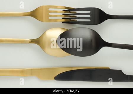 Forchetta dorata e nera, coltello e cucchiaio su sfondo bianco; posate; taglio; posa creativa piatta; Art Deco Foto Stock