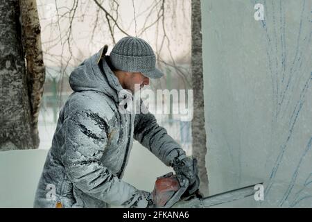 Lo scultore tagli un ghiaccio figura fuori di ghiaccio da una motosega per Natale Foto Stock
