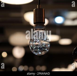 la lampadina con filamenti a led risplende in una stanza buia, lo sfondo con luci sfocate Foto Stock