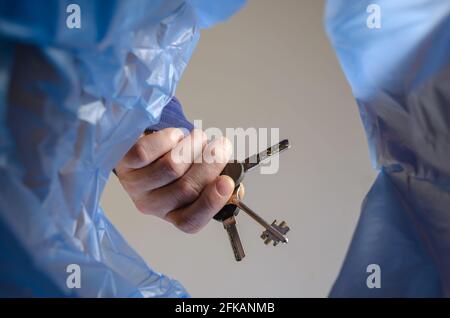 La mano getta le chiavi nel cestino. Un uomo tiene un mazzo di chiavi di porta sopra una lattiera di cestino. Vista dal basso. All'interno Foto Stock