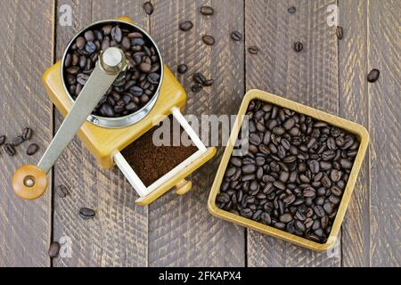 Macinacaffè in legno d'epoca con caffè macinato all'interno Ad una scatola di legno piena di robusta molto scura chicchi di caffè Foto Stock