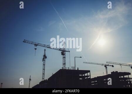 cantiere con gru su sfondo tramonto. sagome di edifici Foto Stock