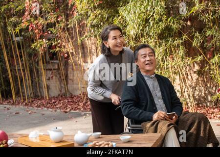 Sua moglie di donne anziane che spingono una sedia a rotelle Foto Stock